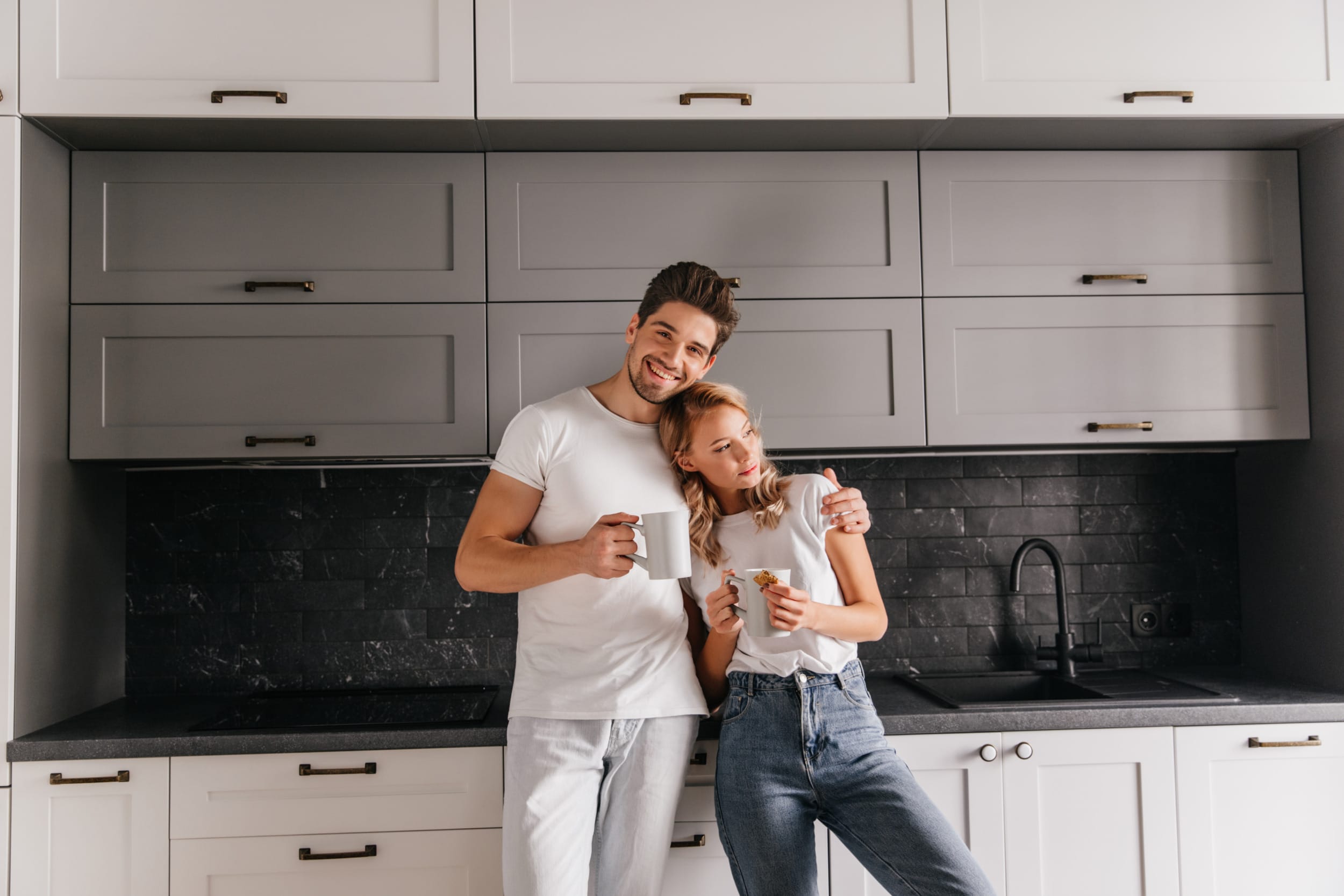stress free A young couple enjoying their new bespoke kitchen and drinking a coffee